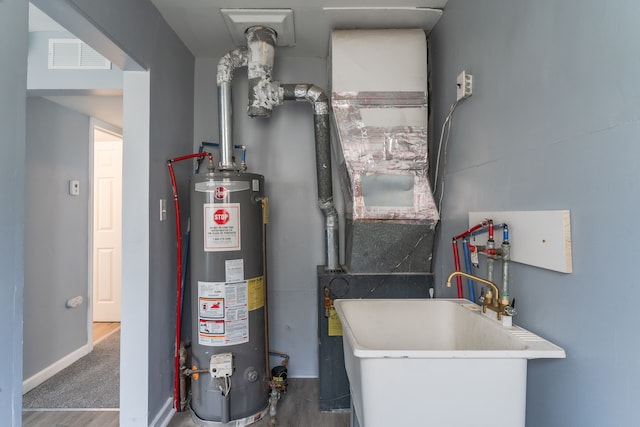 utilities featuring gas water heater, a sink, and visible vents