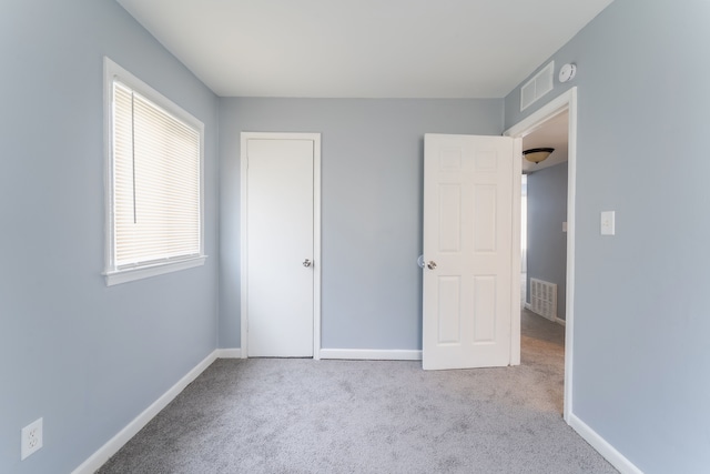 unfurnished bedroom with light colored carpet, visible vents, and baseboards