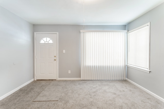 foyer entrance with baseboards and light colored carpet