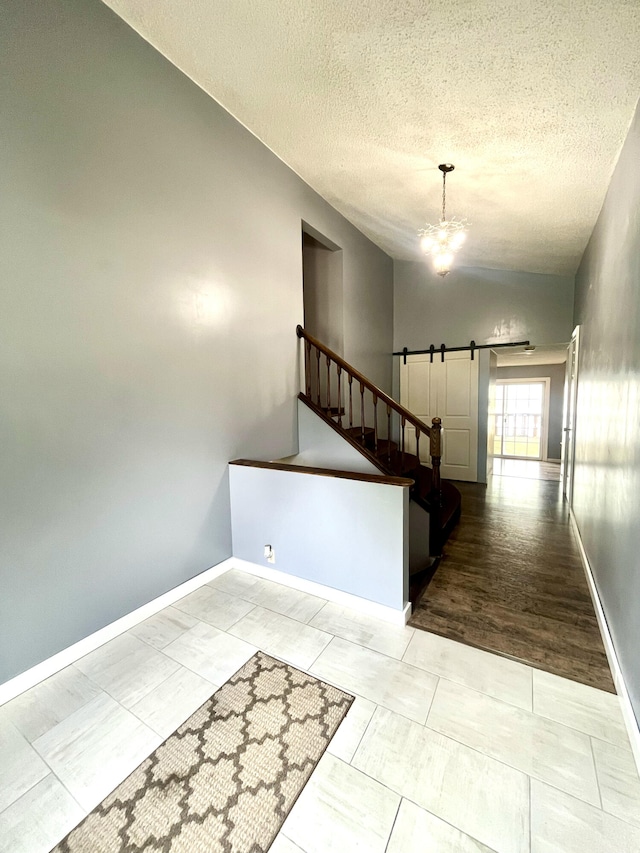2264 Lynn Dr, Saint Joseph, MI 49085 - stairway featuring a chandelier, a textured ceiling, a barn door, baseboards, and vaulted ceiling