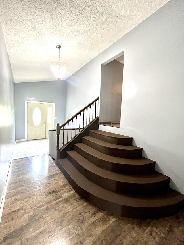 2264 Lynn Dr, Saint Joseph, MI 49085 - stairway with wood finished floors, a chandelier, a textured ceiling, and lofted ceiling