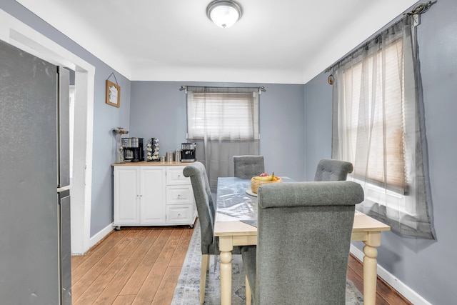 dining area with light wood-type flooring and baseboards