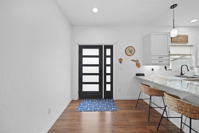 foyer entrance with dark wood-style floors, a textured wall, baseboards, and recessed lighting