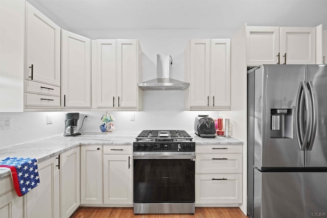 kitchen featuring wall chimney exhaust hood, white cabinetry, and stainless steel appliances