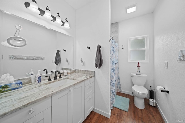 bathroom with toilet, baseboards, wood finished floors, and vanity