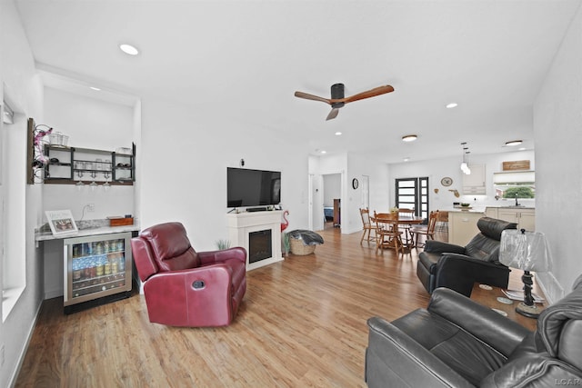 living area with light wood finished floors, beverage cooler, wet bar, and recessed lighting