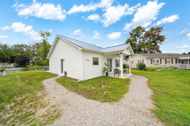 exterior space featuring a yard, a standing seam roof, a patio, and metal roof