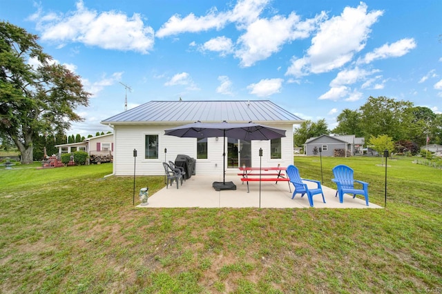 back of house featuring metal roof, a patio, a yard, and a standing seam roof