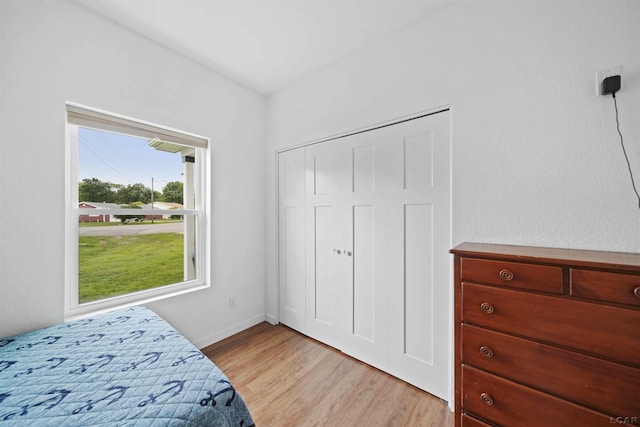 bedroom with a closet, light wood-style flooring, and baseboards