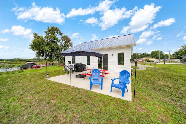 rear view of property featuring a yard, metal roof, and a patio