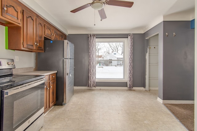 kitchen with appliances with stainless steel finishes, brown cabinetry, light countertops, baseboards, and ceiling fan