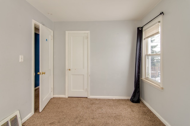 spare room with visible vents, light colored carpet, and baseboards