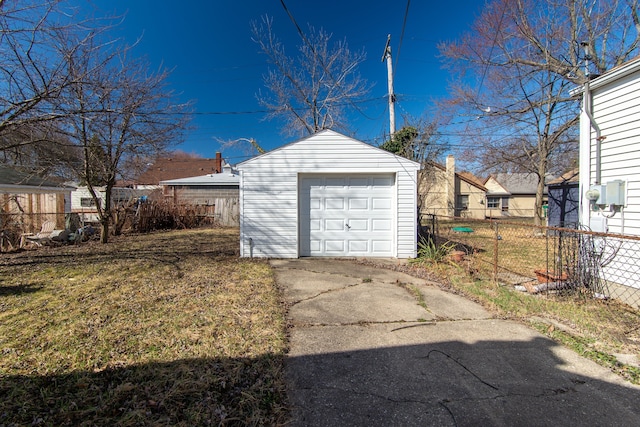 detached garage featuring concrete driveway and fence