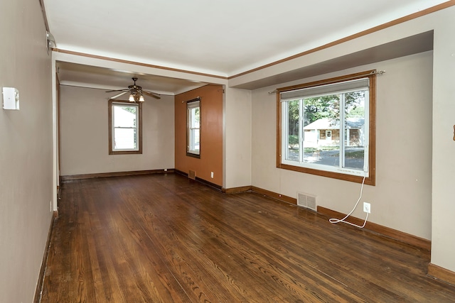 spare room with baseboards, visible vents, dark wood finished floors, and a ceiling fan