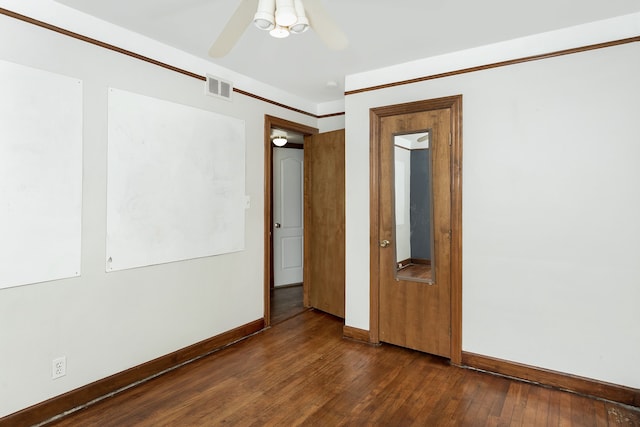 spare room featuring a ceiling fan, dark wood-style flooring, visible vents, and baseboards