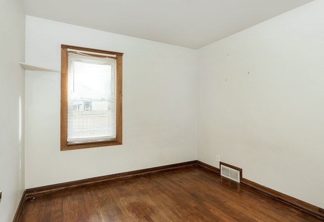 spare room featuring dark wood finished floors, visible vents, and baseboards