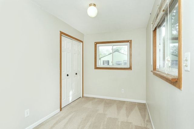 interior space featuring a healthy amount of sunlight, light carpet, and baseboards