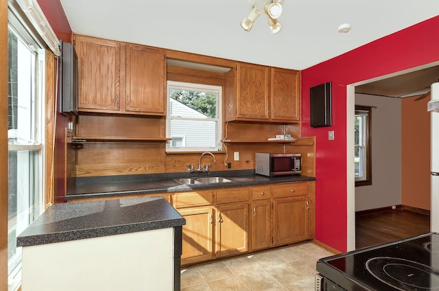 kitchen featuring dark countertops, range with electric cooktop, stainless steel microwave, and a sink