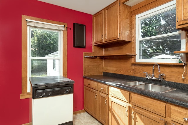 kitchen with dark countertops, brown cabinets, dishwasher, and a sink