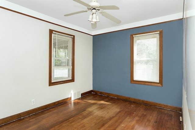 unfurnished room with dark wood-style floors, a wealth of natural light, visible vents, and baseboards