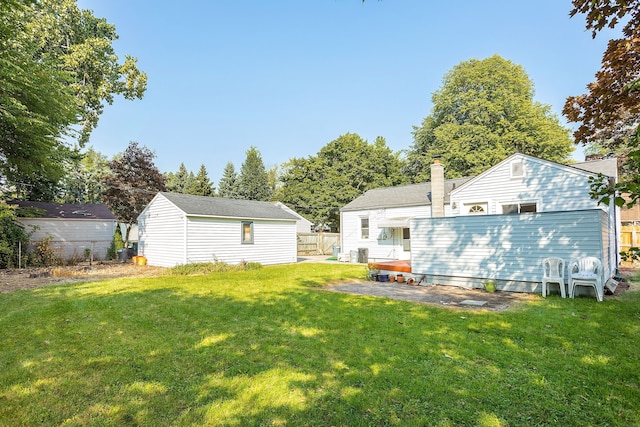 back of house with a chimney, fence, and a lawn