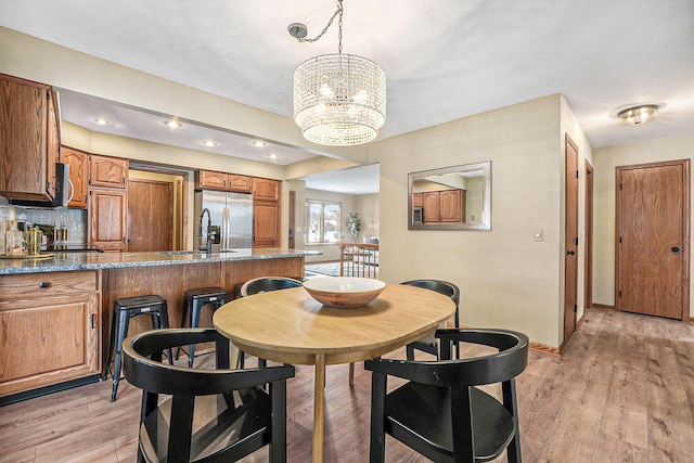 dining space with light wood-style flooring, baseboards, and an inviting chandelier