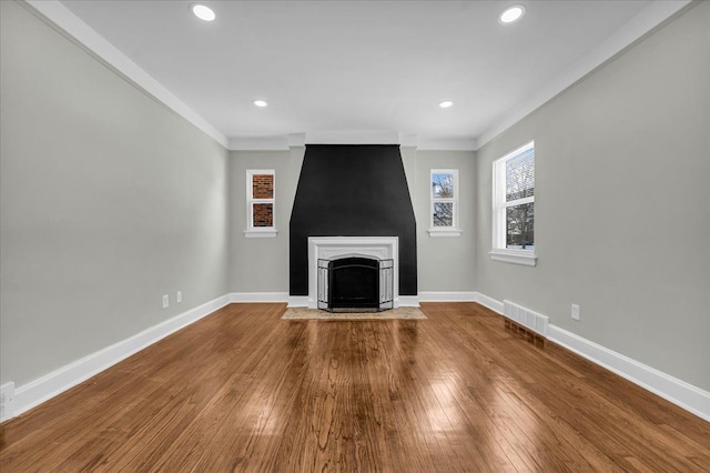 unfurnished living room with a fireplace with flush hearth, wood finished floors, visible vents, and baseboards