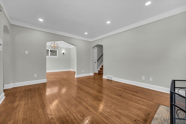 unfurnished living room featuring arched walkways, recessed lighting, wood finished floors, visible vents, and baseboards