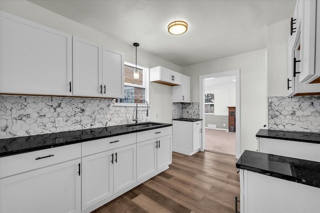 kitchen with dark wood-style flooring, a sink, white cabinetry, hanging light fixtures, and decorative backsplash