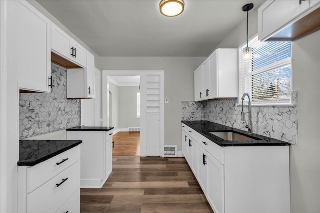 kitchen with dark wood-type flooring, a sink, visible vents, white cabinetry, and hanging light fixtures