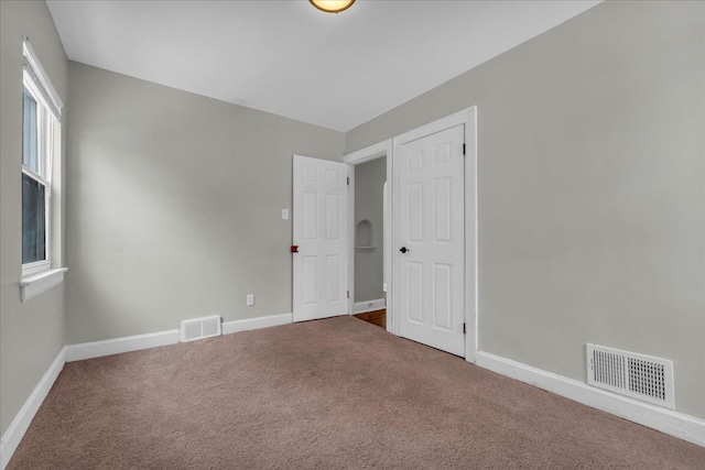 carpeted spare room featuring baseboards and visible vents