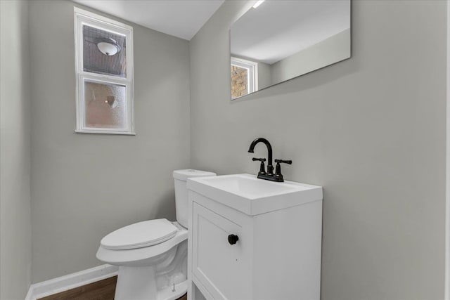 bathroom with toilet, baseboards, wood finished floors, and vanity