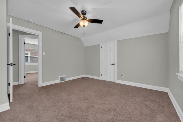 interior space with light carpet, visible vents, baseboards, and lofted ceiling