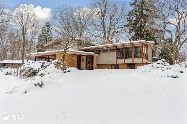 exterior space featuring a garage, a chimney, and brick siding