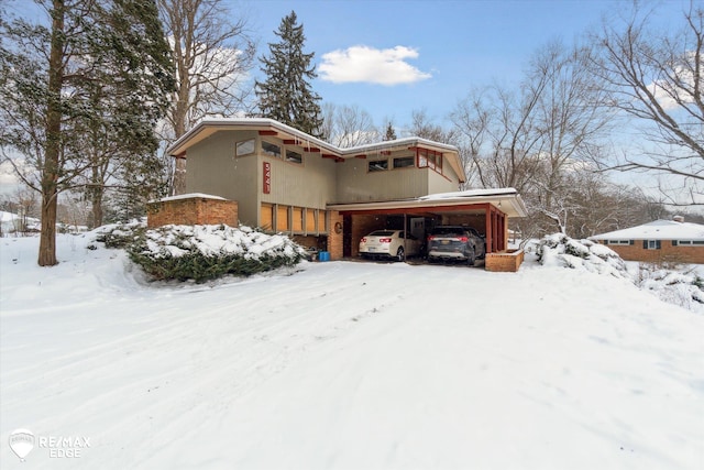 view of snowy exterior with a garage and brick siding