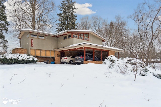 view of front facade with a garage, a carport, and brick siding