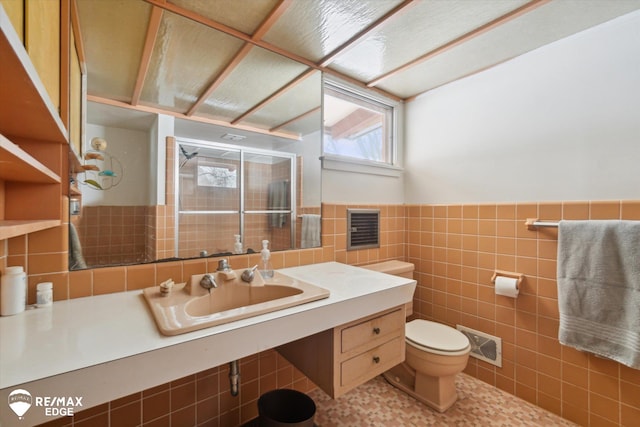 bathroom featuring toilet, visible vents, vanity, tile walls, and wainscoting