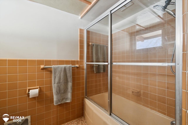 bathroom with a wainscoted wall, combined bath / shower with glass door, and tile walls