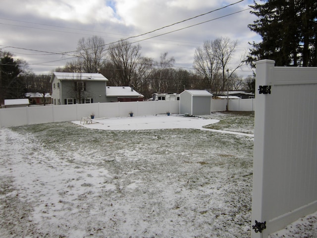 yard covered in snow with a fenced backyard, an outdoor structure, and a shed