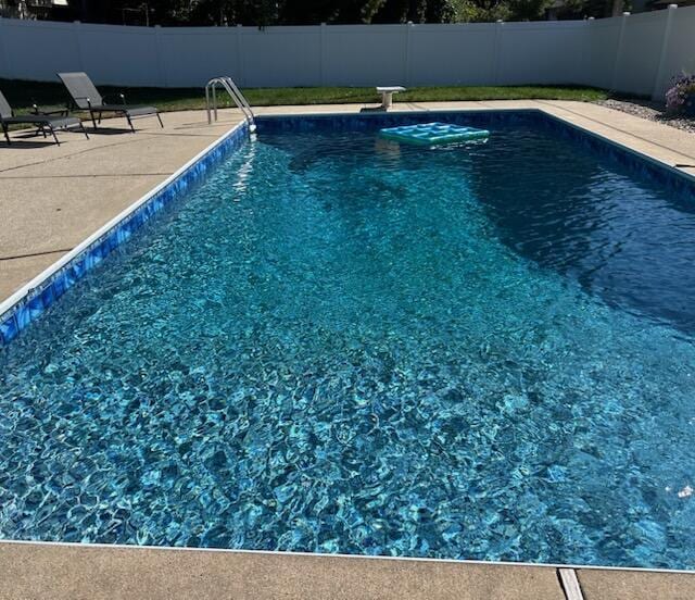 view of pool with a fenced in pool, a fenced backyard, and a diving board