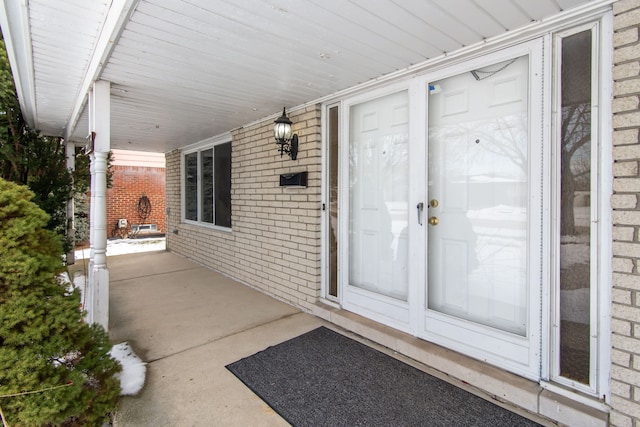 entrance to property with covered porch and brick siding