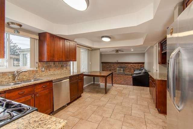 kitchen with a raised ceiling, decorative backsplash, appliances with stainless steel finishes, open floor plan, and a sink