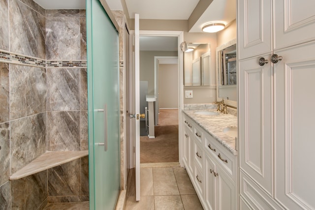 bathroom featuring double vanity, a stall shower, a sink, and tile patterned floors