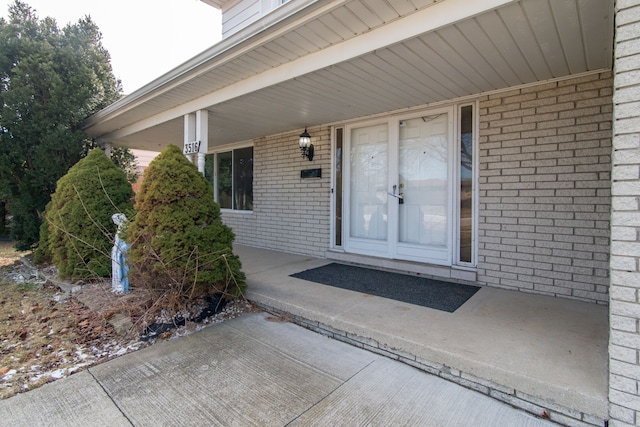 entrance to property with brick siding and a porch