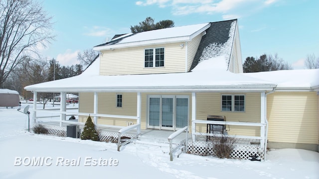 snow covered house with a porch and central AC