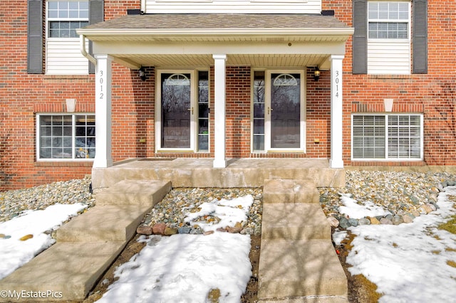 view of exterior entry with covered porch and brick siding