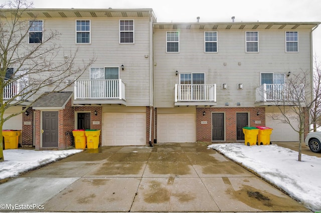 back of property featuring a garage, driveway, and brick siding