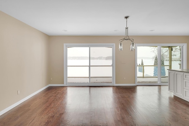 unfurnished room with a healthy amount of sunlight, baseboards, and dark wood-style flooring