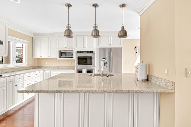 kitchen featuring light stone counters, stainless steel appliances, a sink, white cabinetry, and hanging light fixtures