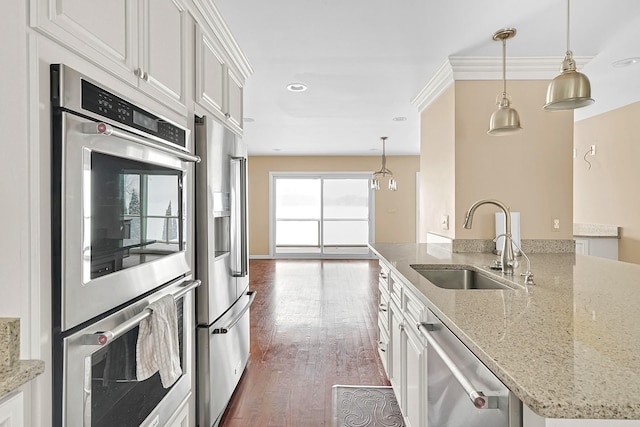 kitchen featuring hanging light fixtures, white cabinetry, stainless steel appliances, and a sink